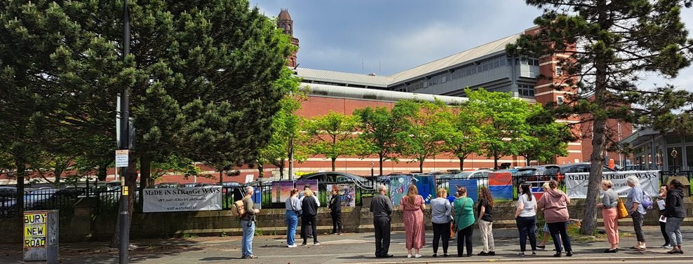 A crowd gathered outside HMP Manchester to view the canvases chained to the prison railings for the Made In Strange Ways exhibition