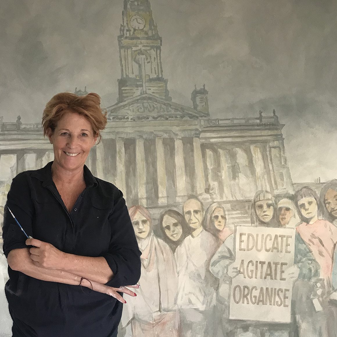 Louise Garman beside her monochrome mural of a protest march, painted for a Unison meeting room