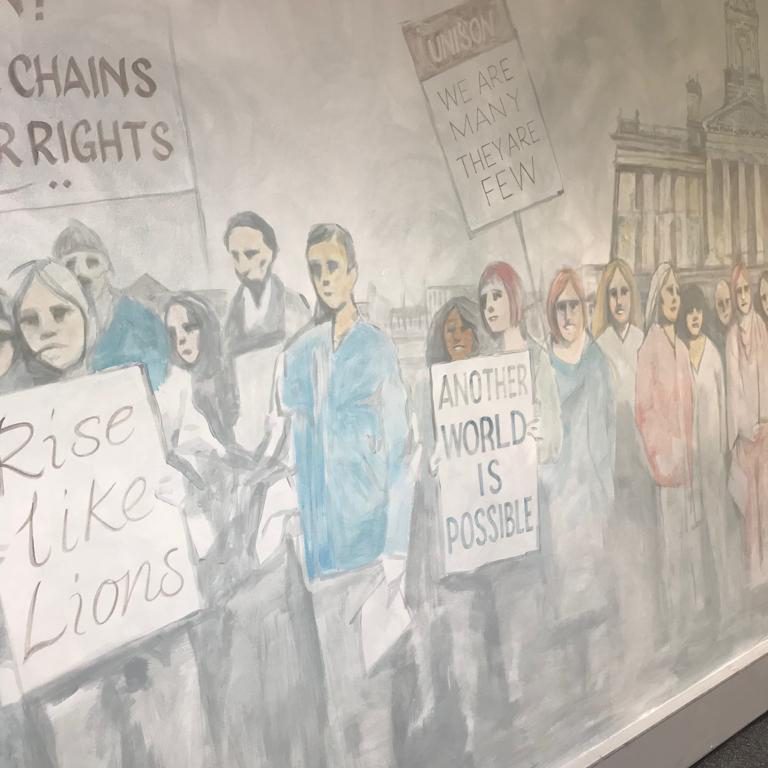 Detail of the monochrome protest mural, with placards reading Rise Like Lions and Another World Is Possible
