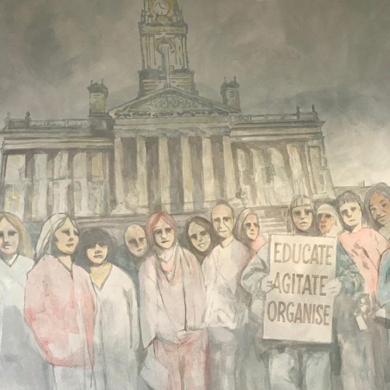 Detail of the monochrome protest mural, with a placard reading Educate Agitate Organise in front of a civic building