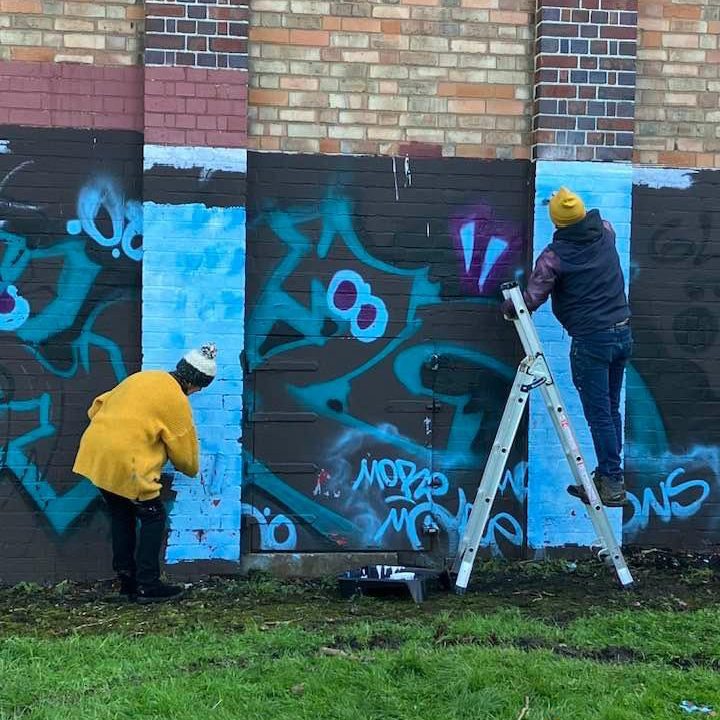 Louise Garman and an assistant painting over graffiti on the Trittiford Park building
