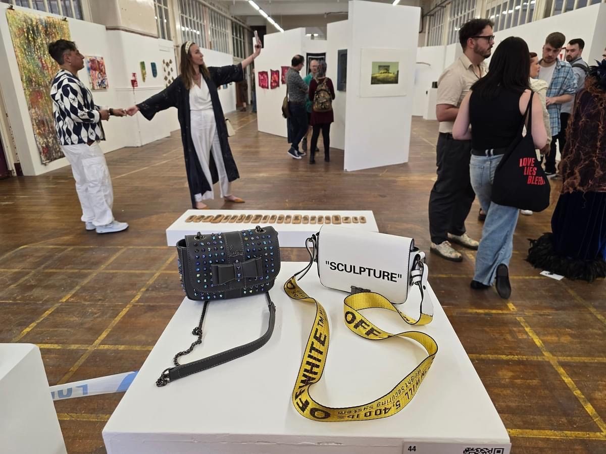 A private view with a plinth displaying counterfeit designer handbags labelled ‘Sculpture’, part of the Strangeways installation, at the neo:artists Open exhibition, Rogue Gallery, Manchester