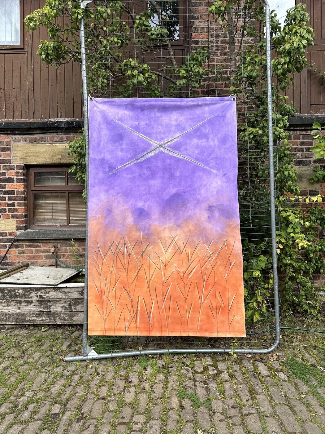 Hand-dyed canvas hanging, exhibited outdoors on a metal frame