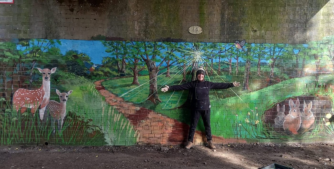 Louise Garman beside the completed woodland mural in Birmingham