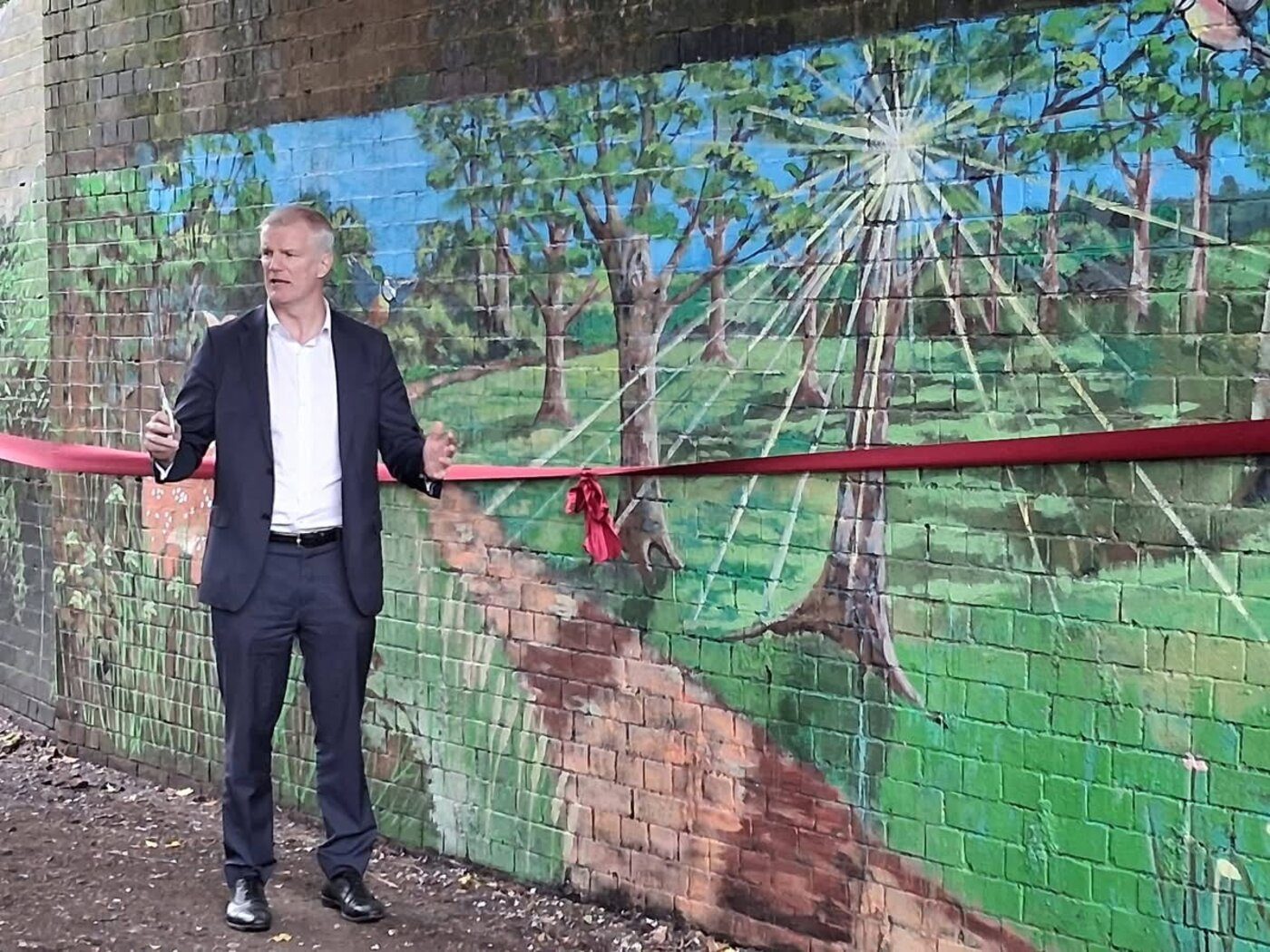 Al Carns MP cutting the ribbon at the mural opening