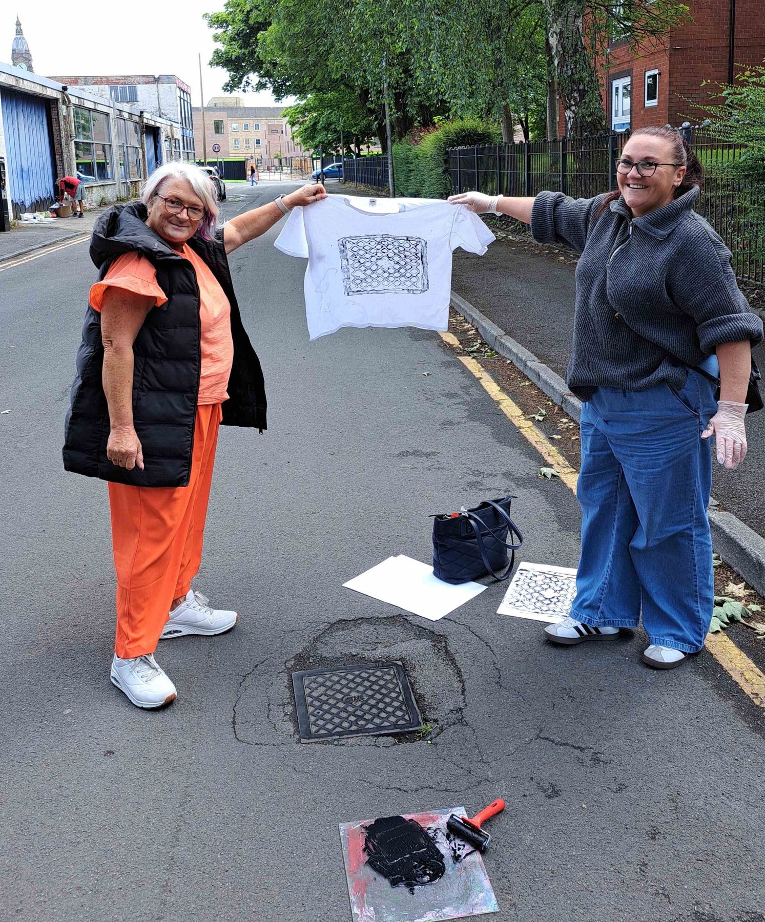 Two participants holding a t-shirt printed from a pothole grid pattern