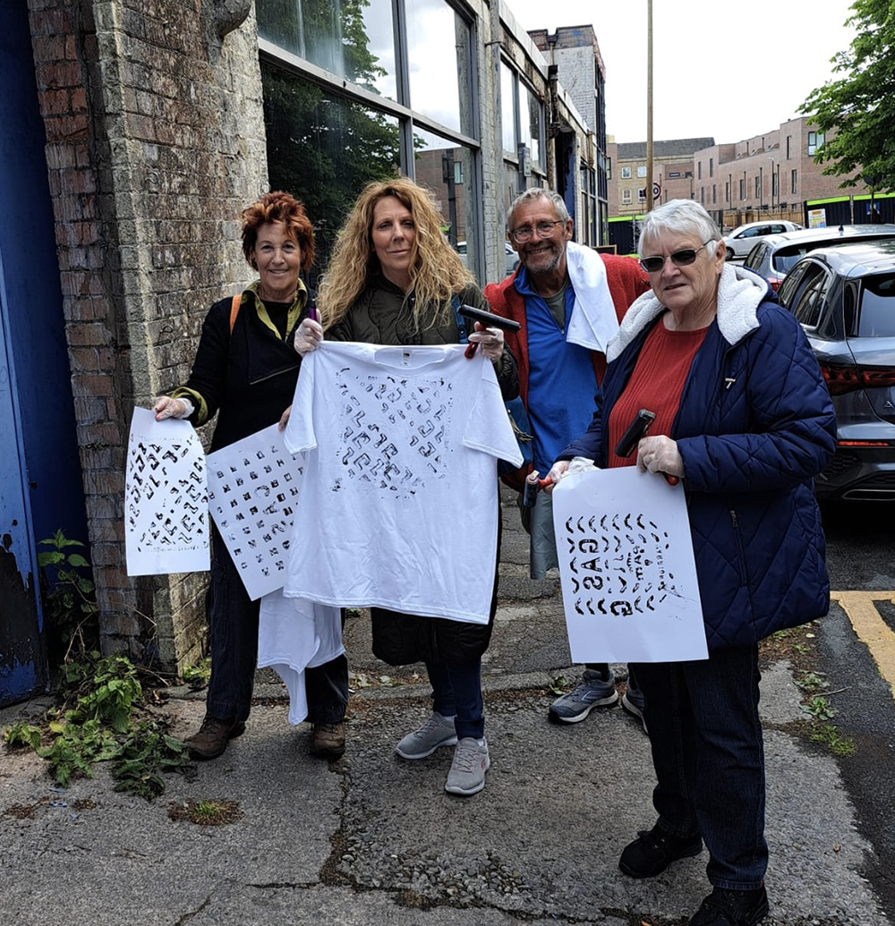 Participants from the Showing How It Is project holding their printed grid artworks on a Bolton street