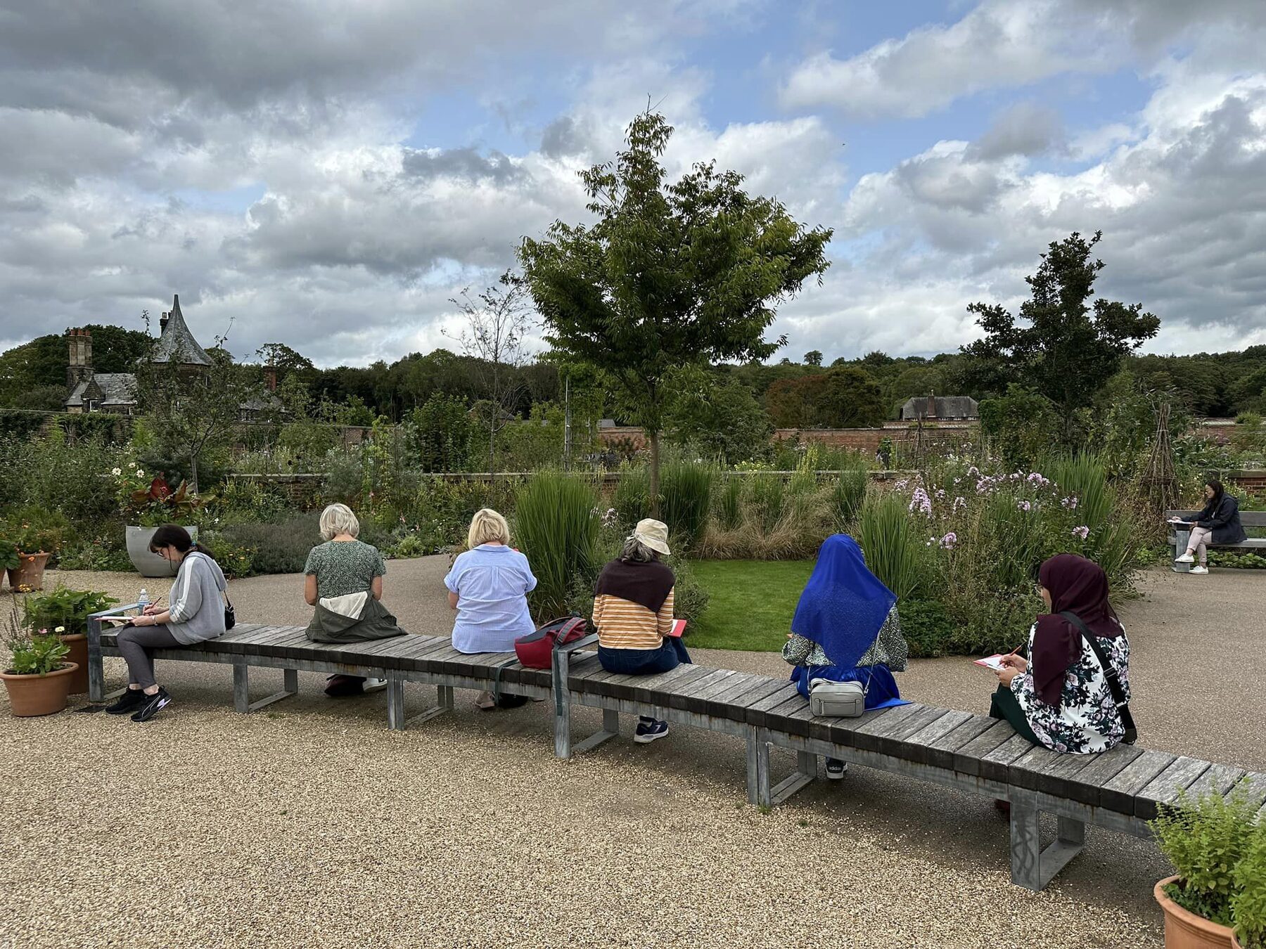 Workshop participants sketching the planting beds from a long bench in the garden