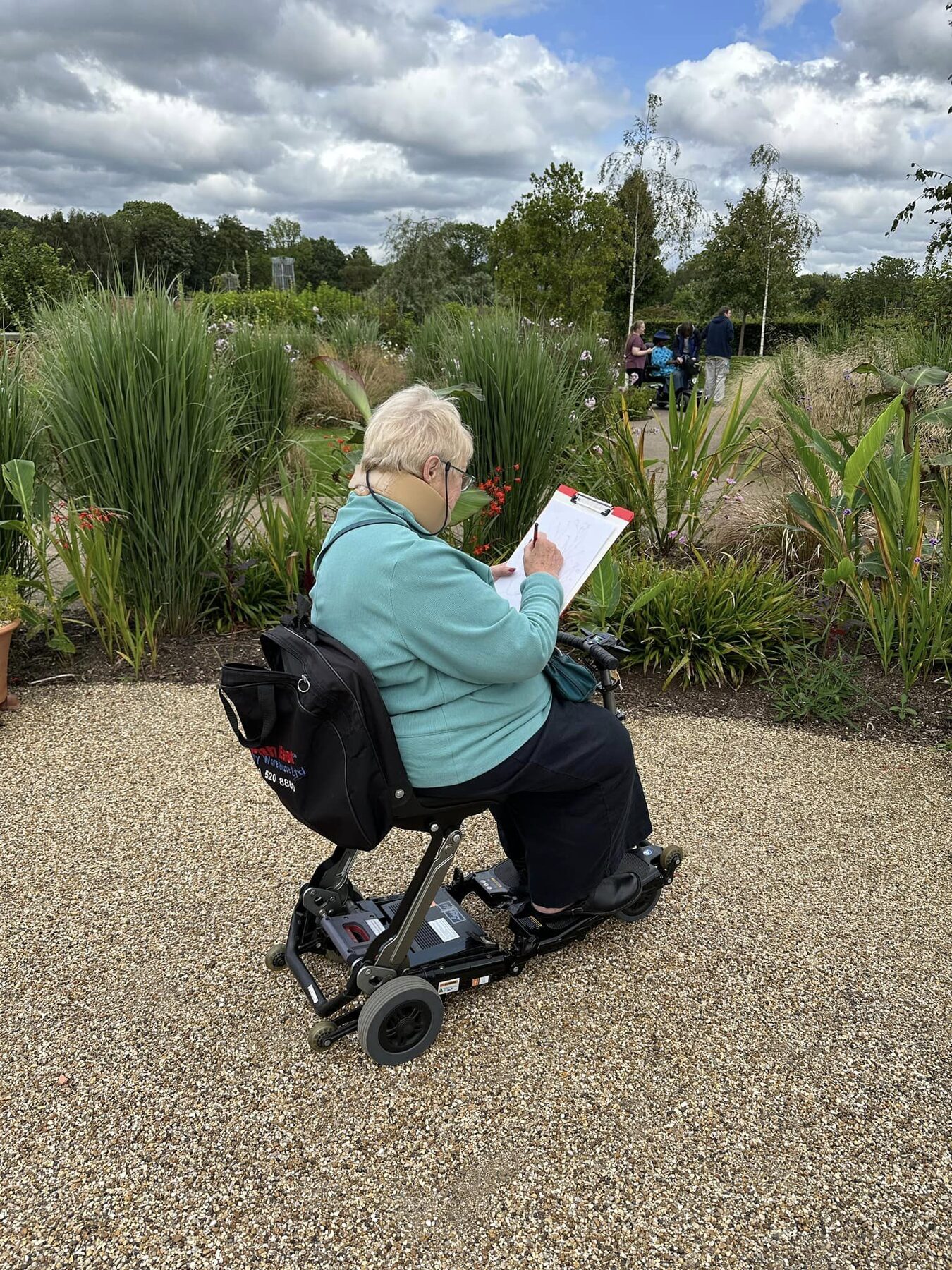 A workshop participant using a mobility scooter, sketching the planting beds at RHS Garden Bridgewater