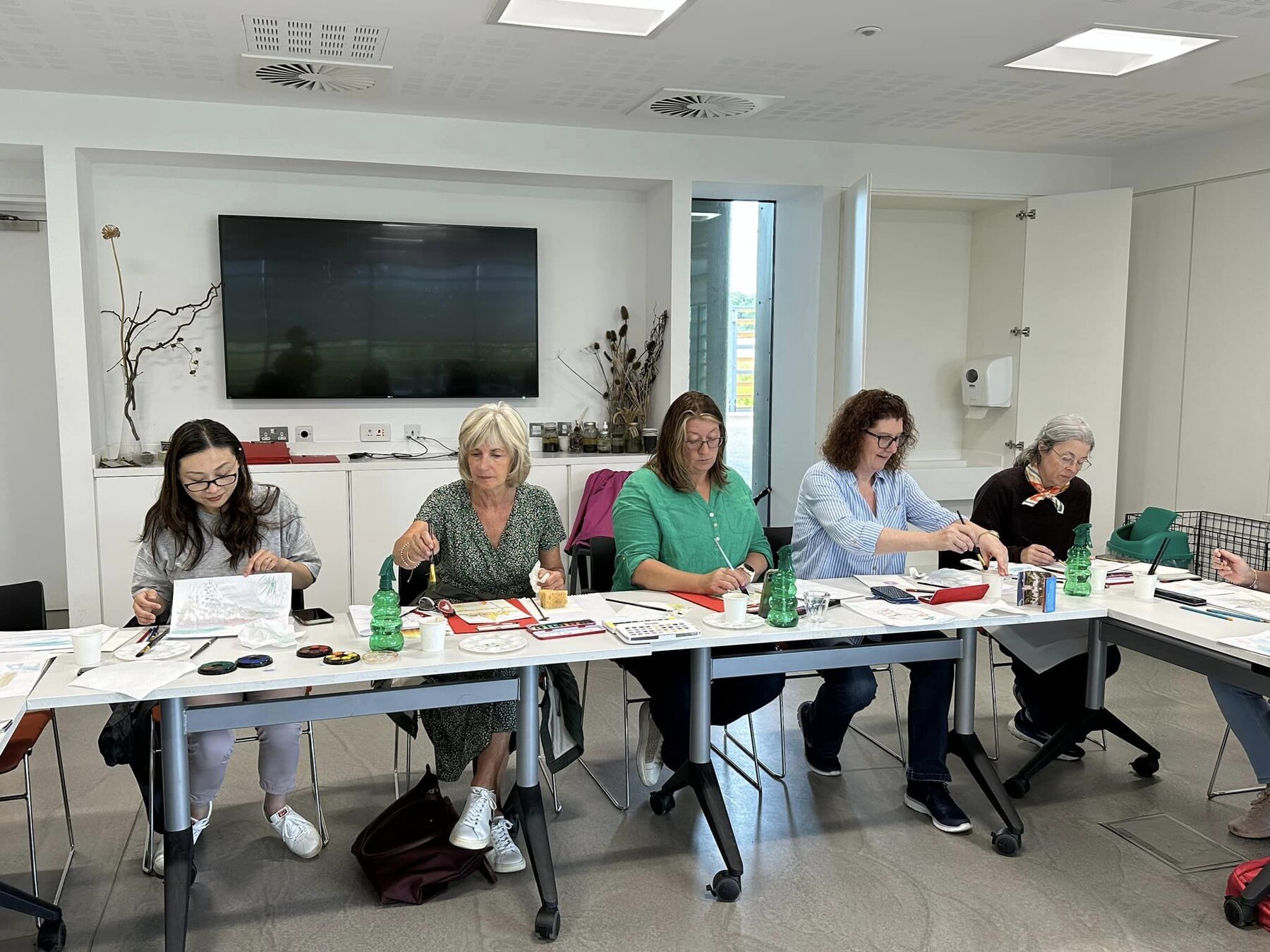 Participants seated at a table sketching and painting during the watercolour workshop