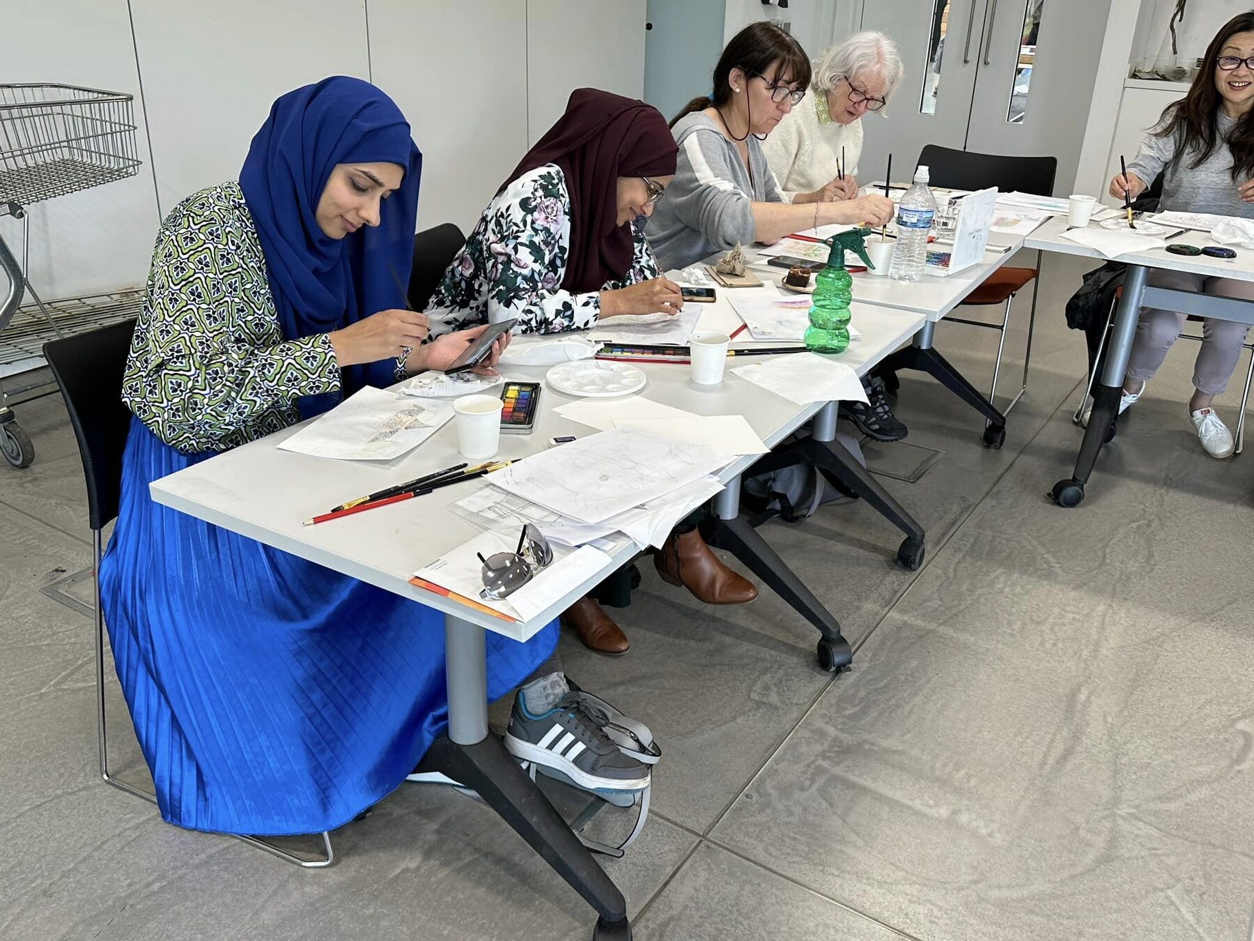Workshop participants painting watercolours together at a table at RHS Garden Bridgewater