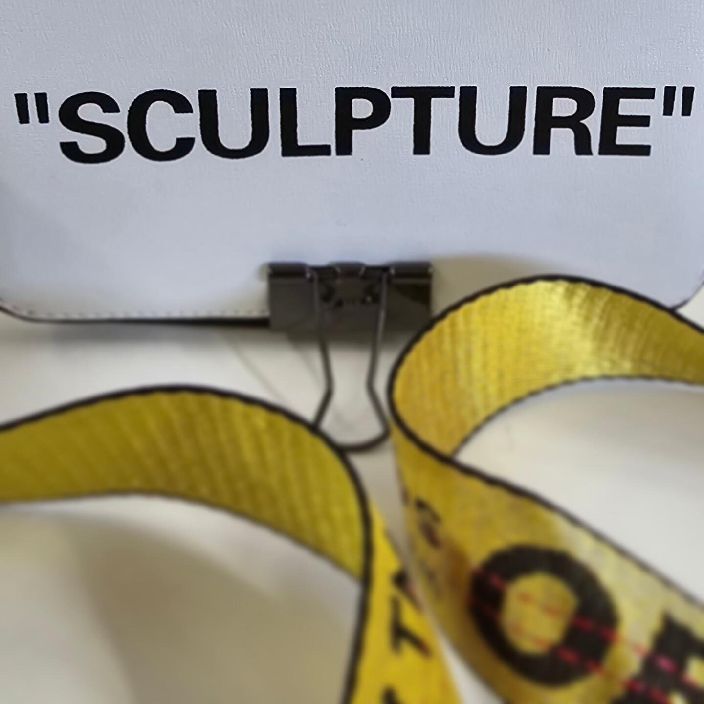 Detail of Louise Garman's Sculpture assemblage piece, with a designer-style bag and yellow security tape