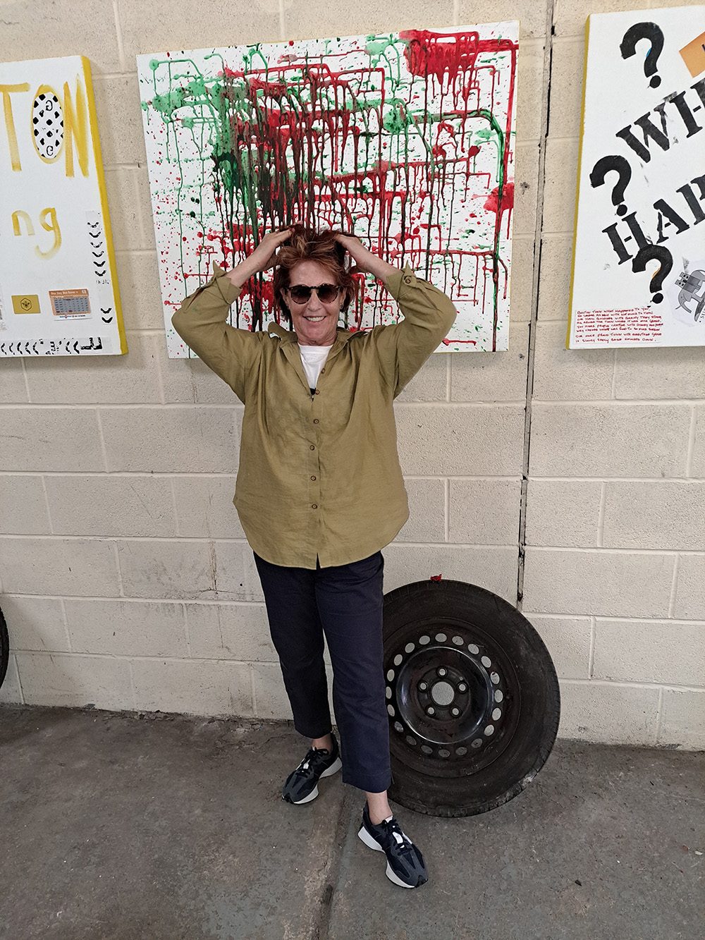 Louise Garman in front of a paint-splattered canvas from the exhibition