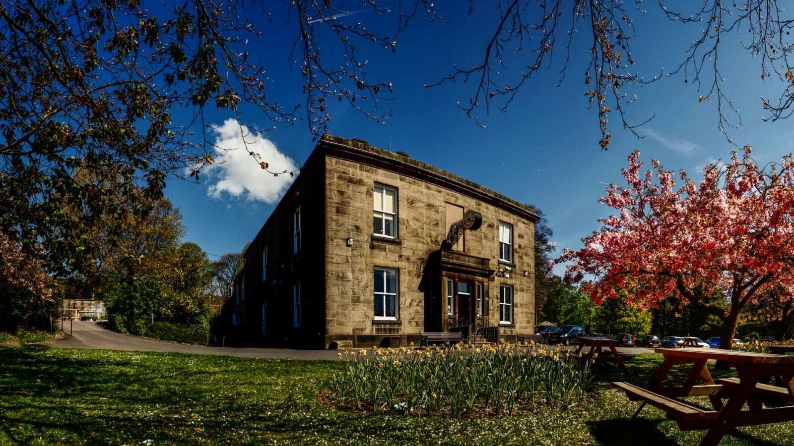 The Whitaker, Rossendale Museum and Art Gallery, a stone building set in parkland with blossom trees