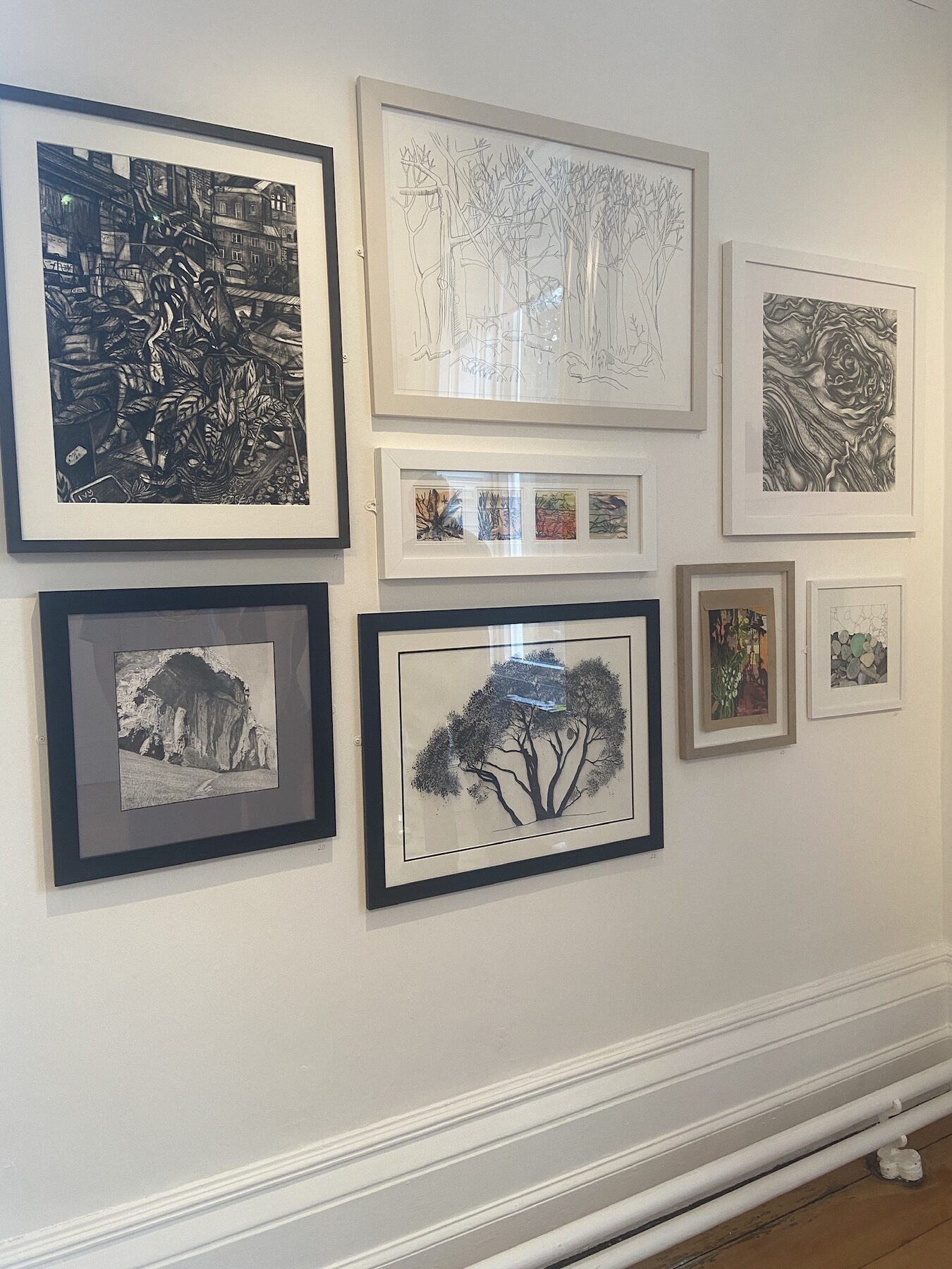 A gallery wall at The Whitaker hung with framed drawings and mixed media pieces from the 60 + 10 Group Drawing Exhibition