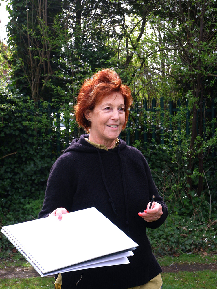 Louise Garman holding a sketchbook in the park