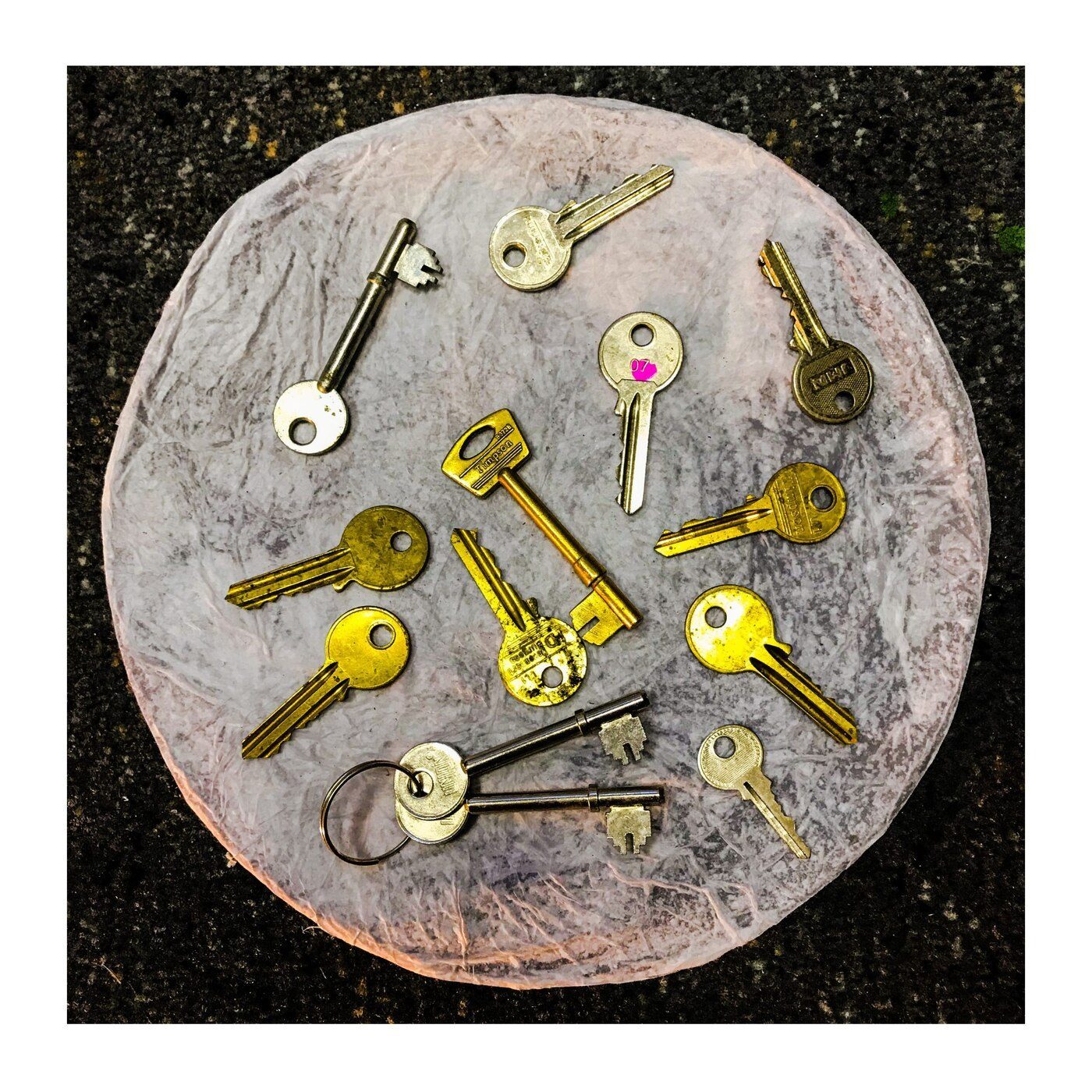 Flat-lay assemblage of vintage keys on a paper disc