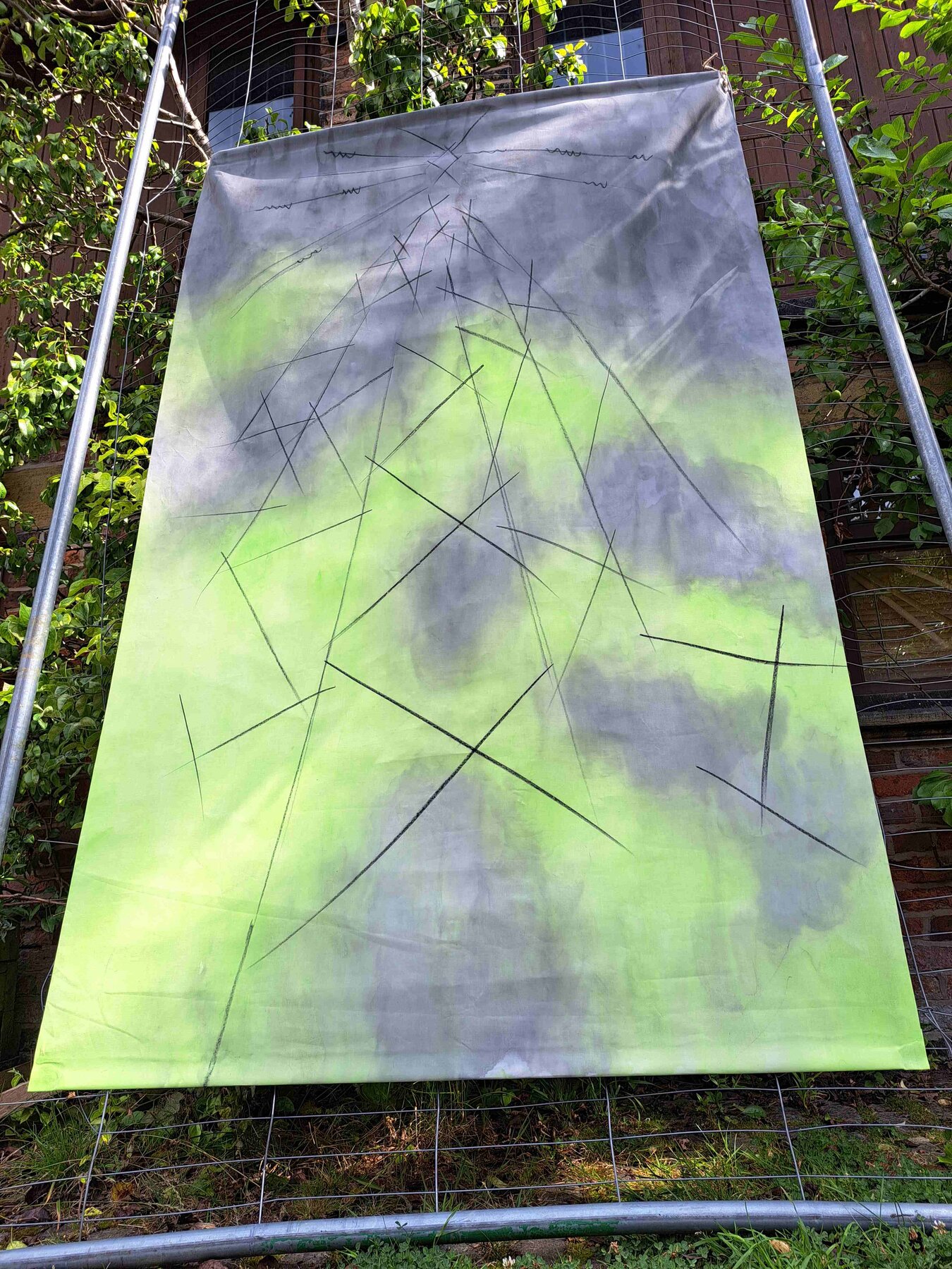 Hand-dyed fabric hanging in green and grey with charcoal cross-hatch marks